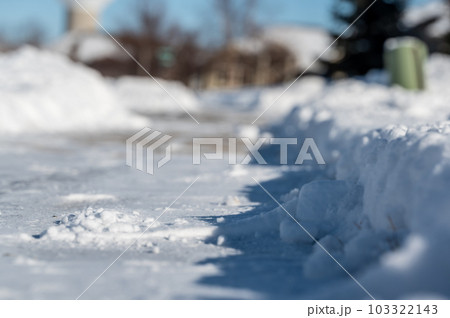 Selective focus ground level view of snow blown sidewalk section with path continuing.  103322143