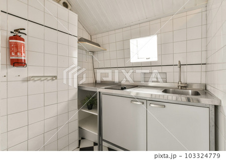 a small kitchen with white tiles on the walls and ceiling above it is a red fire exor in the sink a small kitchen with white tiles on the walls and ceiling above it is a red fire exor in the sink 103324779