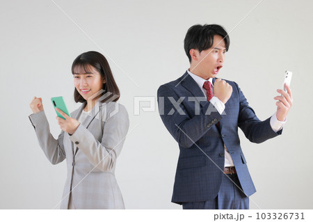 スマホを見てやったーとガッツポーズするビジネスウーマンとビジネスマン_1 103326731