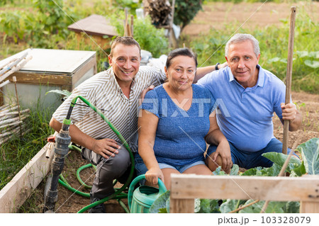 Portrait of happy farmers with gardening tools in garden after work Portrait of happy farmers with gardening tools in garden after work 103328079