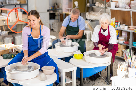 Young woman learning how to create pottery on potter wheel in workshop Young woman learning how to create pottery on potter wheel in workshop 103328246
