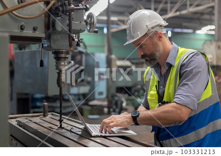 engineer wear white hard hat and wearing safety uniform using laptop working steel drill engineer wear white hard hat and wearing safety uniform using laptop working steel drill 103331213