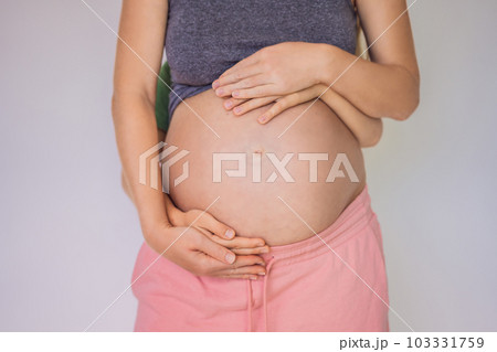 Young beautiful pregnant woman and eldest son. The cute boy put his hands on his mother's belly. Expecting a baby in the family concept. Preparing an older child for a younger one Young beautiful pregnant woman and eldest son. The cute boy put his hands on his mother's belly. Expecting a baby in the family concept. Preparing an older child for a younger one 103331759