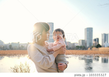 夕暮れに赤ちゃんを抱っこする母 103335327