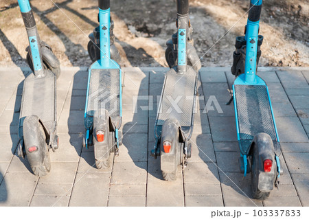 Modern parking for electric scooters on the street. Electric scooter rental in the city. Electric Ride Sharing Scooters Lined Up and Ready to Rent 103337833
