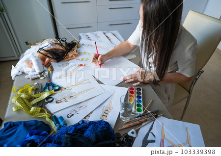 Woman draws sketches of swimwear with a pencil.  103339398