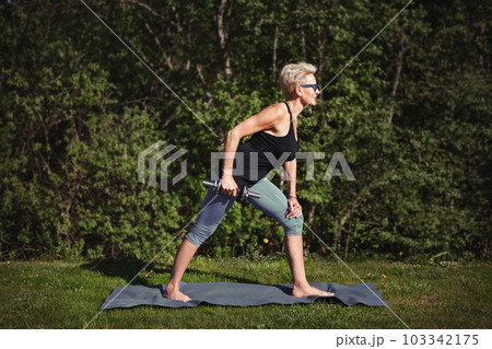 Senior woman enjoys workout, exercises with dumbbell, training body in midst of nature, dedicating herself to healthy lifestyle and staying active. Outdoor fitness 103342175