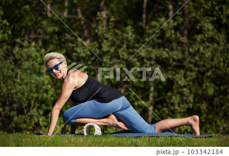 Joyful middle aged woman exercising fitness workout at green nature, outdoors. Mature female model engaged in physical activity and has well trained body. Active and joyful lifestyle 103342184