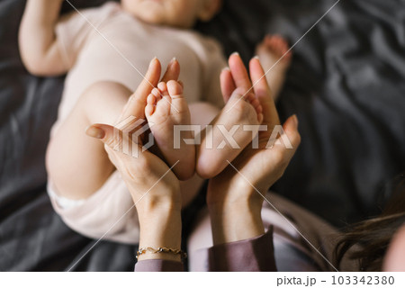 Baby feet in the hands of the mother. Tiny legs of a newborn baby on female hands close-up. 103342380