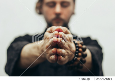Fingers pointing forward to the camera. Hands folded in prayer. Close-up of palm together. The beads on the wrist. The rosary on hand. 103342604