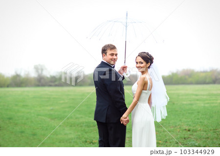 bride and groom on a rainy wedding day walking 103344929