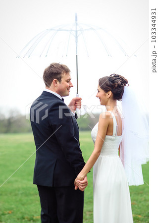 bride and groom on a rainy wedding day walking 103344931