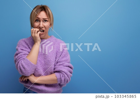 portrait of a frightened sad blonde young woman in a lavender sweater on a bright plain background portrait of a frightened sad blonde young woman in a lavender sweater on a bright plain background 103345865