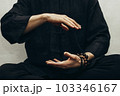 A man in black shirt sitting and doing qigong. Hands direct energy. Prayer, gratitude.Practicing monk. Qi energy. Yoga pose. Close up 103346167
