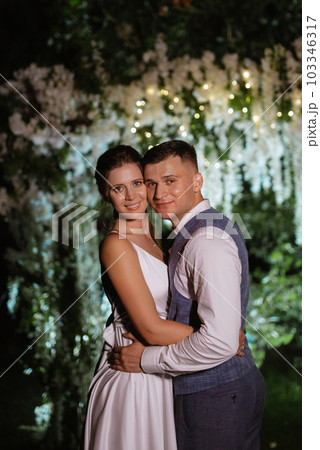 couple of newlyweds on the evening illuminated arch 103346317