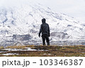 A man stands alone against the backdrop of a large mountain. Bad weather 103346387