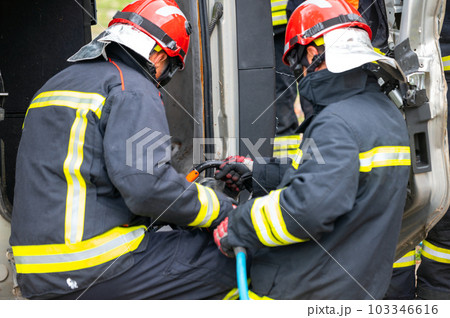 Firefighters using hydraulic tools during a rescue operation training. Rescuers unlock the passenger Firefighters using hydraulic tools during a rescue operation training. Rescuers unlock the passenger 103346616