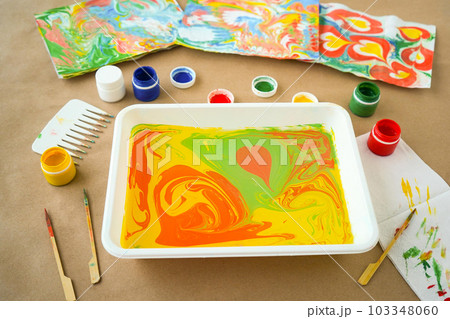 abstract drawing Ebru and set of tools on table. Traditional Turkish Ebru technique. top view. Children development concept abstract drawing Ebru and set of tools on table. Traditional Turkish Ebru technique. top view. Children development concept 103348060