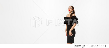 Vertical view of beautiful young woman in luxurious dress, red lips and jewelry, standing with christmas gifts on white background, standing over white background 103348661