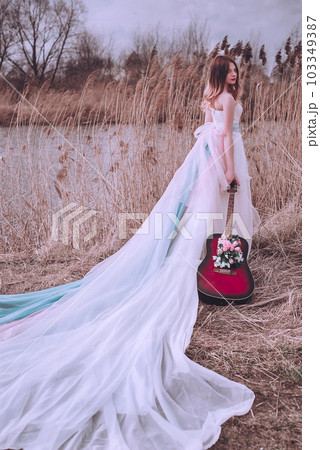 Beautiful romantic european girl with guitar with flowers inside, posing outdoors. Concept of music and nature. Spring time. Beautiful romantic european girl with guitar with flowers inside, posing outdoors. Concept of music and nature. Spring time. 103349387