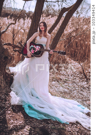 Beautiful romantic european girl with guitar with flowers inside, posing outdoors. Concept of music and nature. Spring time. Beautiful romantic european girl with guitar with flowers inside, posing outdoors. Concept of music and nature. Spring time. 103349414
