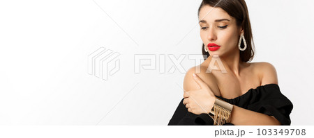 Fashion and beauty concept. Elegant woman with red lips, black dress, showing earrings and jewelry, white background Fashion and beauty concept. Elegant woman with red lips, black dress, showing earrings and jewelry, white background 103349708