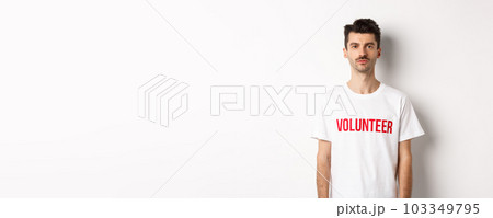 Serious young male volunteer in white t-shirt looking at camera, ready to help 103349795
