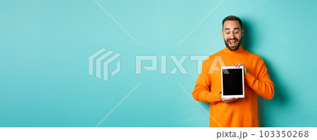 Technology. Cheerful adult man looking and showing digital tablet screen, standing over light blue background Technology. Cheerful adult man looking and showing digital tablet screen, standing over light blue background 103350268