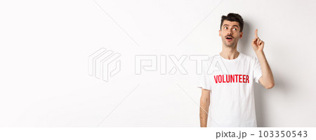 Handsome young man in volunteer t-shirt having an idea, raising finger and saying suggestion, white background 103350543