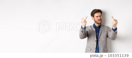 Rude businessman in suit showing middle finger, fuck you gesture, look annoyed and pissed-off, standing on white background Rude businessman in suit showing middle finger, fuck you gesture, look annoyed and pissed-off, standing on white background 103351139