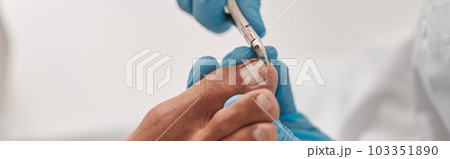 Professional podiatrist uses shny clipper to cut toenail of man in beauty salon 103351890