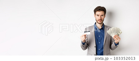 Successful businessman making money, standing in suit with dollar bills and plastic credit card, white background 103352013