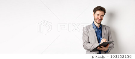 Smiling male manager in suit writing on clipboard, taking notes at office meeting, standing on white background 103352156