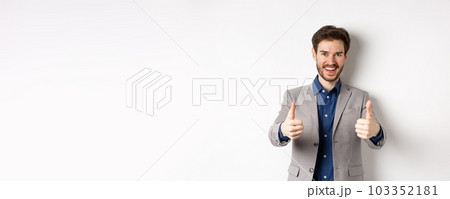 Cheerful and positive young man in business suit showing thumbs up and smiling, like something good, praise good job, standing happy on white background Cheerful and positive young man in business suit showing thumbs up and smiling, like something good, praise good job, standing happy on white background 103352181