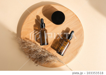 Amber glass bottle on beige background. Wooden branch. Natural skin care SPA beauty product design. Mineral organic oil cosmetics. Minimal Flat lay 103353518