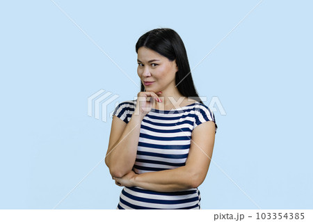 Portrait of a young brunette asian woman is looking at you seducively. Isolated on blue background. Portrait of a young brunette asian woman is looking at you seducively. Isolated on blue background. 103354385