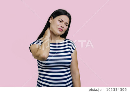 Young asian brunette woman is suffering from neckache. Isolated on pink background. 103354396
