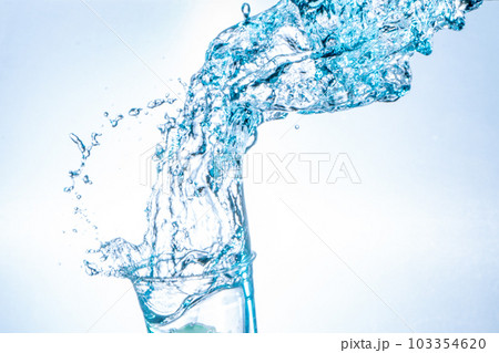 Drinking water splashing from the glass on white background Drinking water splashing from the glass on white background 103354620