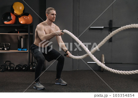 Crossfit athlete doing exercise with battle ropes at gym 103354854