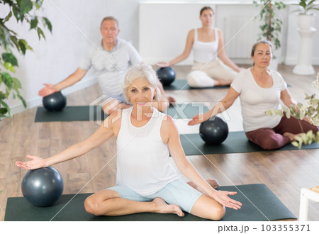 Elderly woman doing pilates with soft ball in studio Elderly woman doing pilates with soft ball in studio 103355371