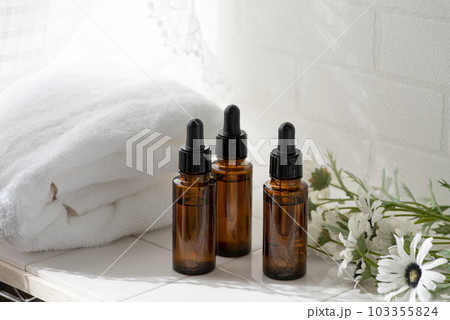 白いタオルとお花とガラス製の茶色いコスメボトル 白いタオルとお花とガラス製の茶色いコスメボトル 103355824