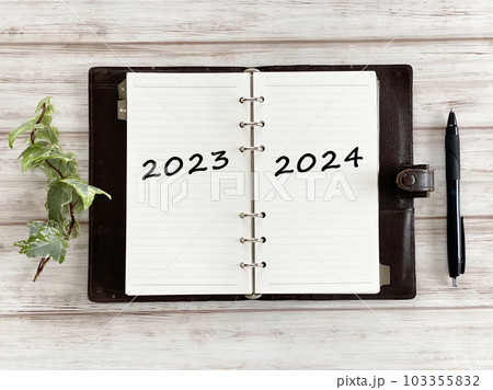 白板の上で開いた手帳とボールペンとツタ_俯瞰_2023と2024文字入り 白板の上で開いた手帳とボールペンとツタ_俯瞰_2023と2024文字入り 103355832