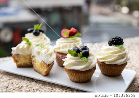 Cupcakes with different fruits on a white plate close-up. 103356558
