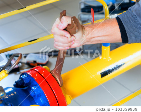 The worker tightens the nut of the gas equipment with an adjustable wrench. hands close up The worker tightens the nut of the gas equipment with an adjustable wrench. hands close up 103359939