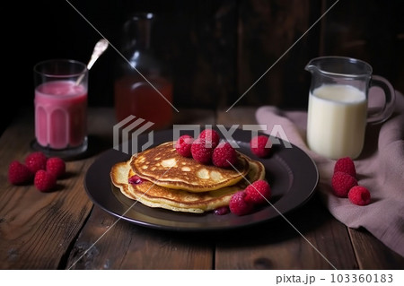 pancake spread with honey and raspberry on a plate accompanied by milk and fruit juice 103360183