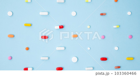 Various white medication tablets and capsules on blue background. Concept of healthcare and medicine. Top view, pattern 103360466