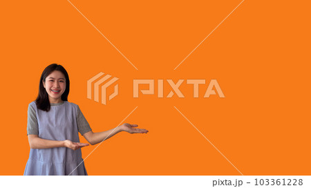 Asian woman with holding copyspace imaginary on the palm to insert an ad, Showing copyspace pointing, Showing her hand to present something on orange background. Asian woman with holding copyspace imaginary on the palm to insert an ad, Showing copyspace pointing, Showing her hand to present something on orange background. 103361228