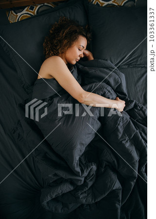 Young woman sleeps in fetal position on an ergonomic bed 103361337
