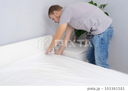 A man makes his cozy bed with fresh bright white 103361581