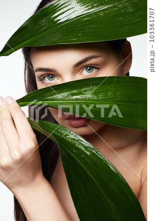 beautiful girl behind the palm. Beautiful young woman with Make-up beautiful girl behind the palm. Beautiful young woman with Make-up 103361707